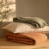 Pile de linge de lit plié sur un plan en chêne clair