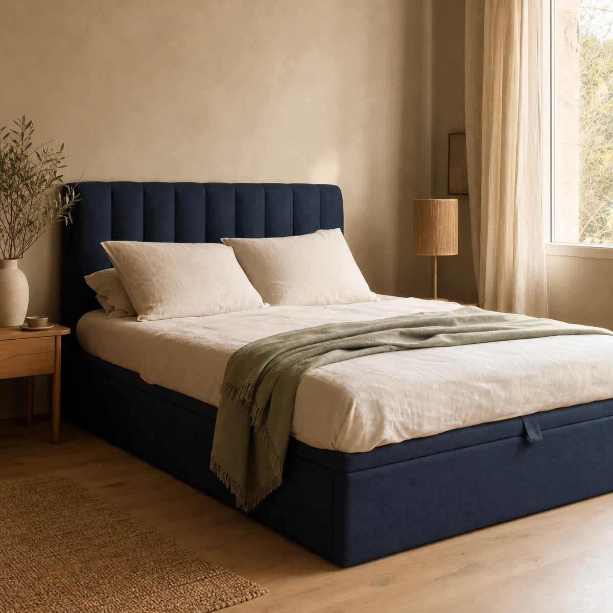 Lit coffre capitonné bleu encre avec linge de lit écru dans une chambre claire