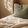 Coin de lit en lin froissé avec coussin vert sauge